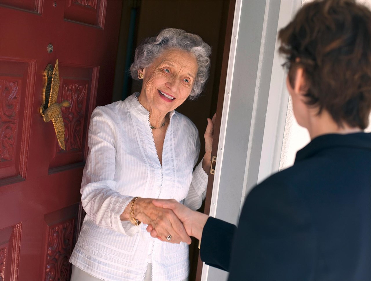 Frau öffnet Wohnungstür